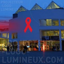Projektion eines Rotlichtbandes im Freien auf ein Gebäude zur Sensibilisierung für die Abschottung