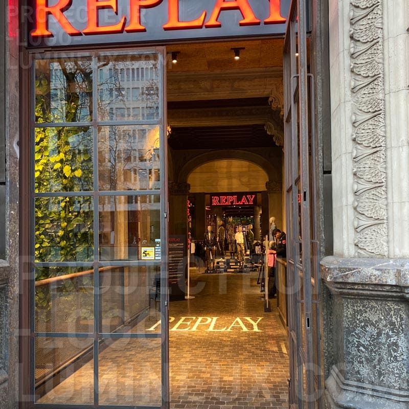 Illuminated logo projection on the floor of the shop entrance